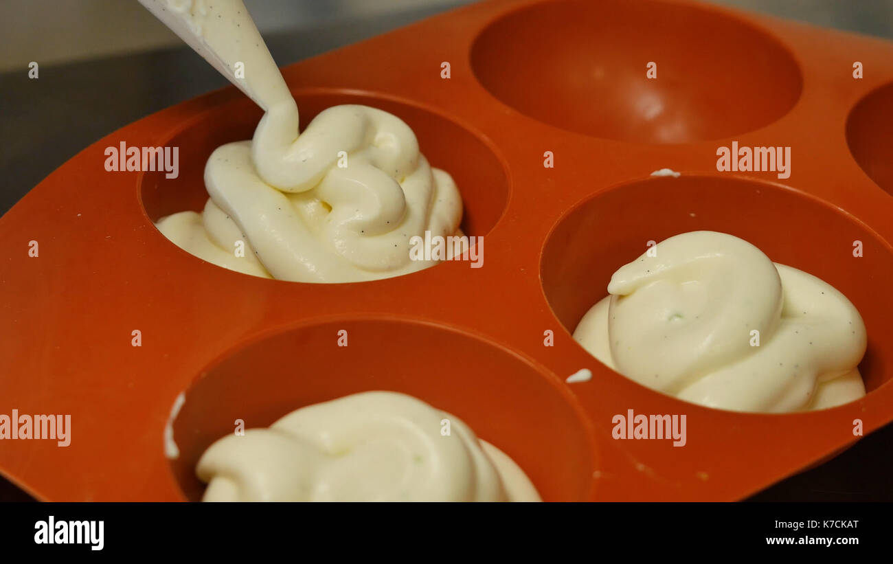 Pastry bag filling a flexible silicone mold with mousse. Gourmet French dessert, closeup Stock