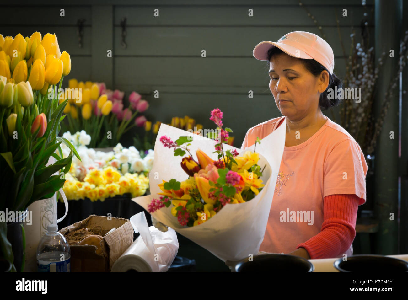 SEATTLE- APR 11, 2014: Unidentified flower vendor at Pikes Place Market arranges a bouquet. The public market is known as a great source of fresh bloo Stock Photo