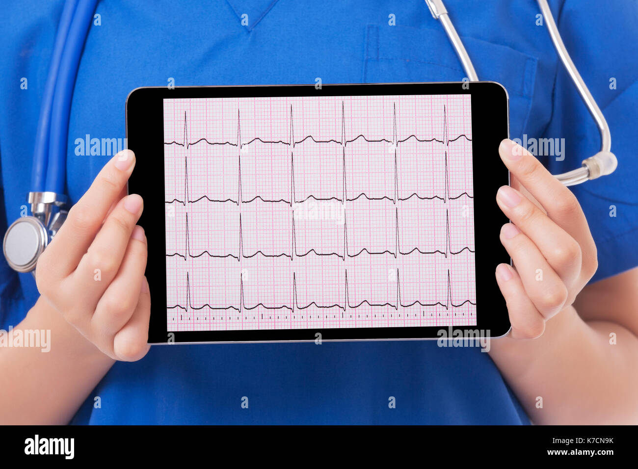 Asian doctor or nurse holding a tablet computer showing an EKG.  With a Clipping Path on the screen Stock Photo