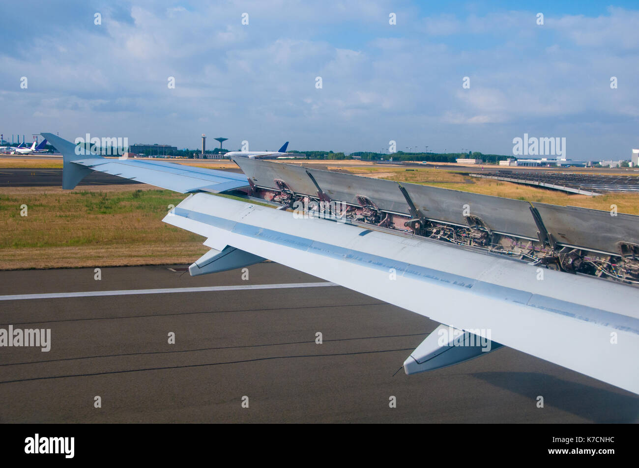 Plane is landing on runway in airport on along landing strip. Flaps are released on the plane wing to top it efficiently. Stock Photo