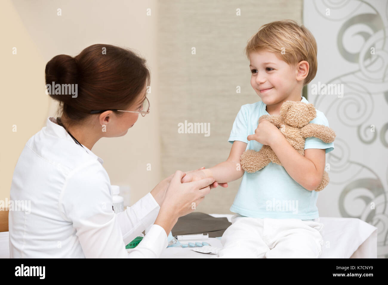 Cute smiling boy at the doctor with his little toy friend, not affraid to visit pediatrician, happy healthy childhood Stock Photo