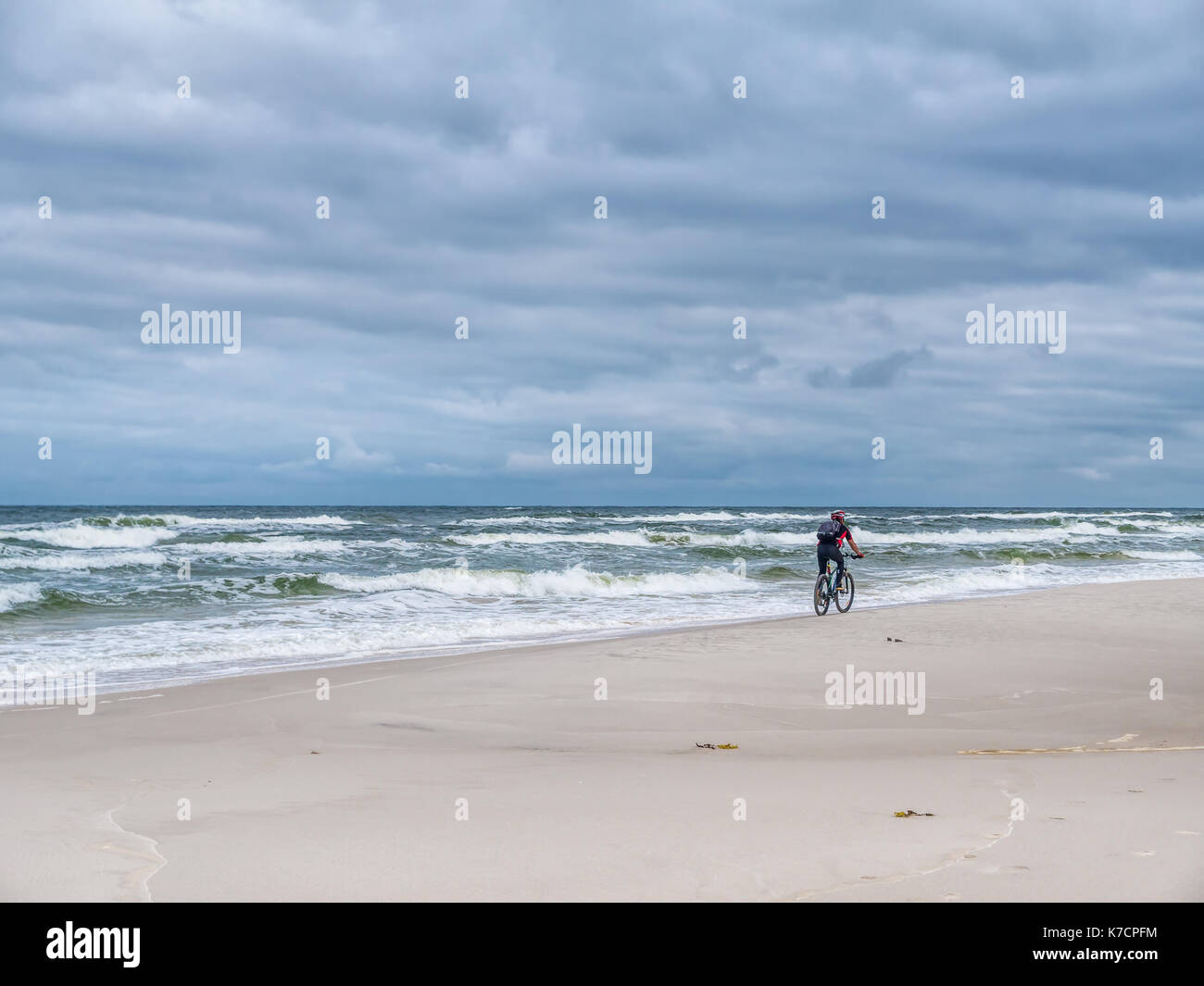 Biker biking along the sandy beach Stock Photo