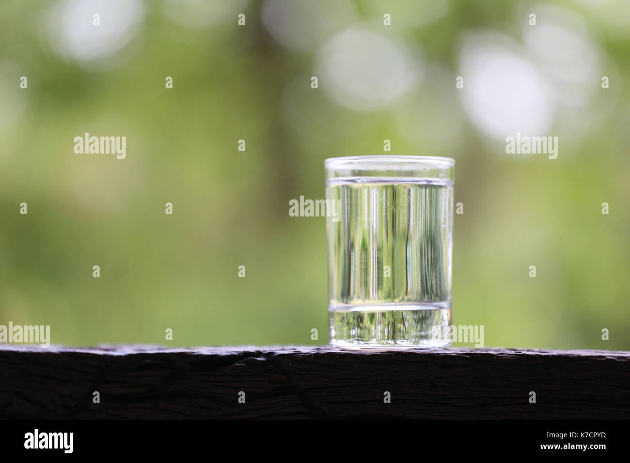 water glass on wooden floor and green nature background for design in your work. Stock Photo