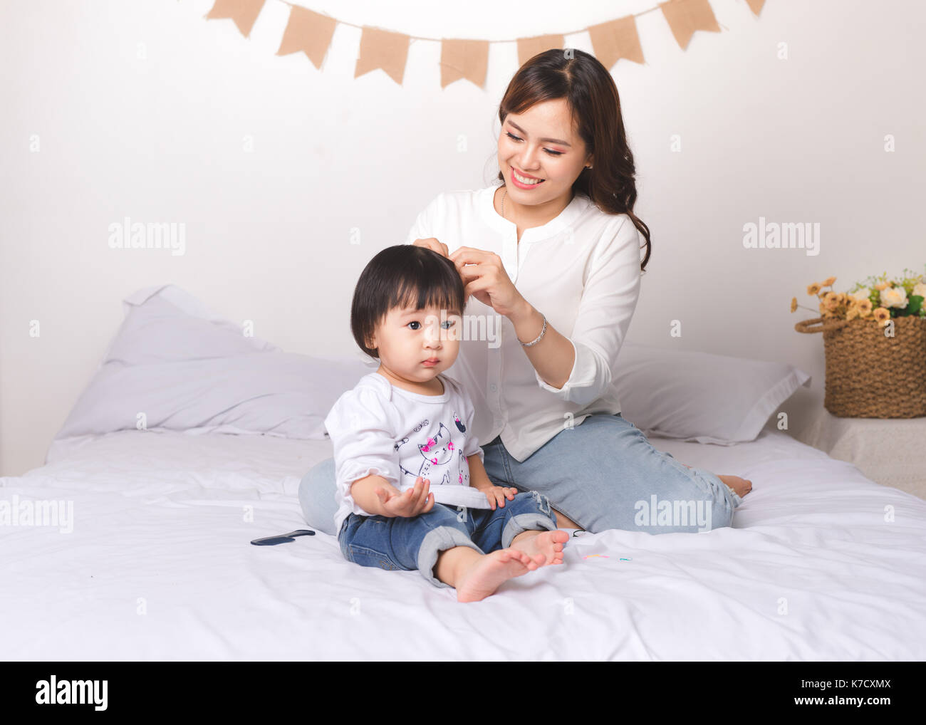 Happy loving family. Mom and child girl are having fun on the bed. Stock Photo