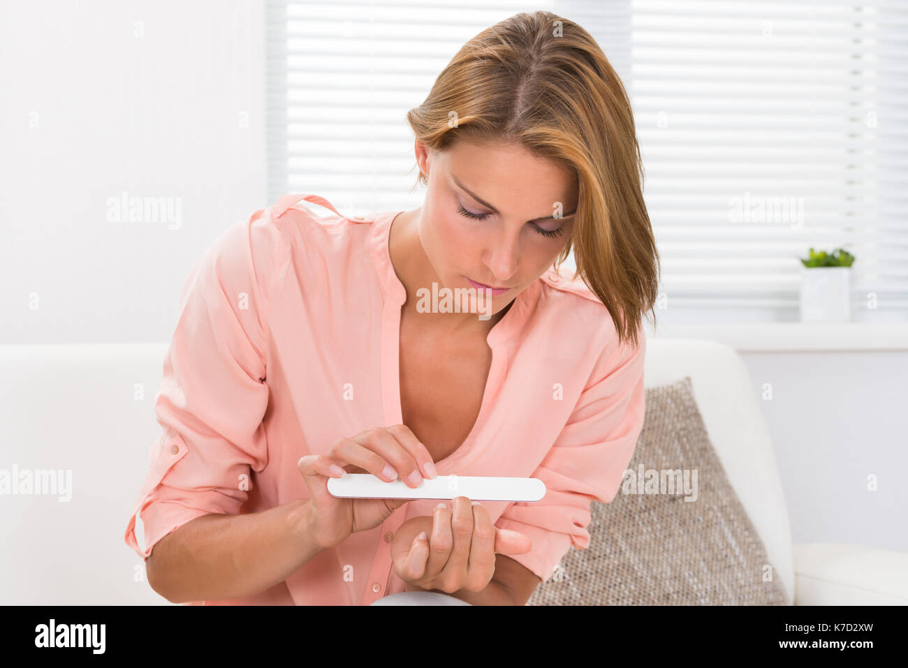 Portrait Of Young Woman Filing Nails With Nail File At Home Stock Photo