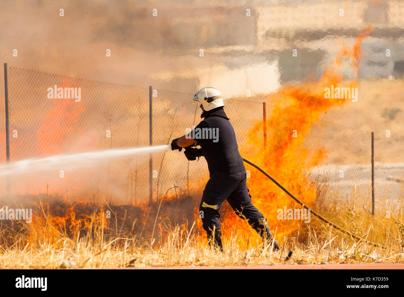 Firefighter putting out fire with hose hires stock photography and
