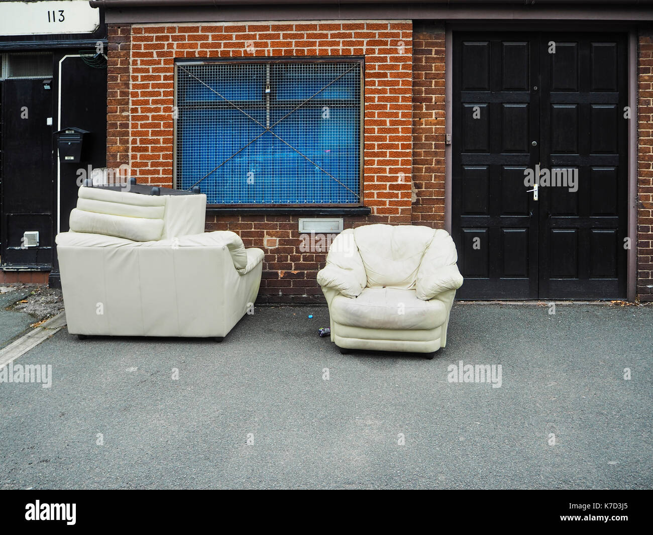 Abandoned sofas outside boarded up shop Stock Photo