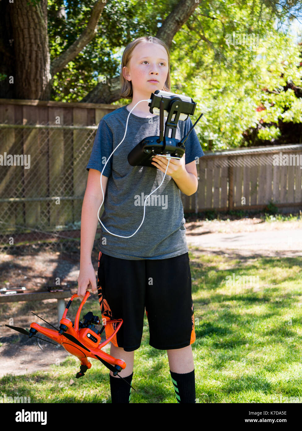 Boy looking away while holding remote control and quadcopter at playground Stock Photo
