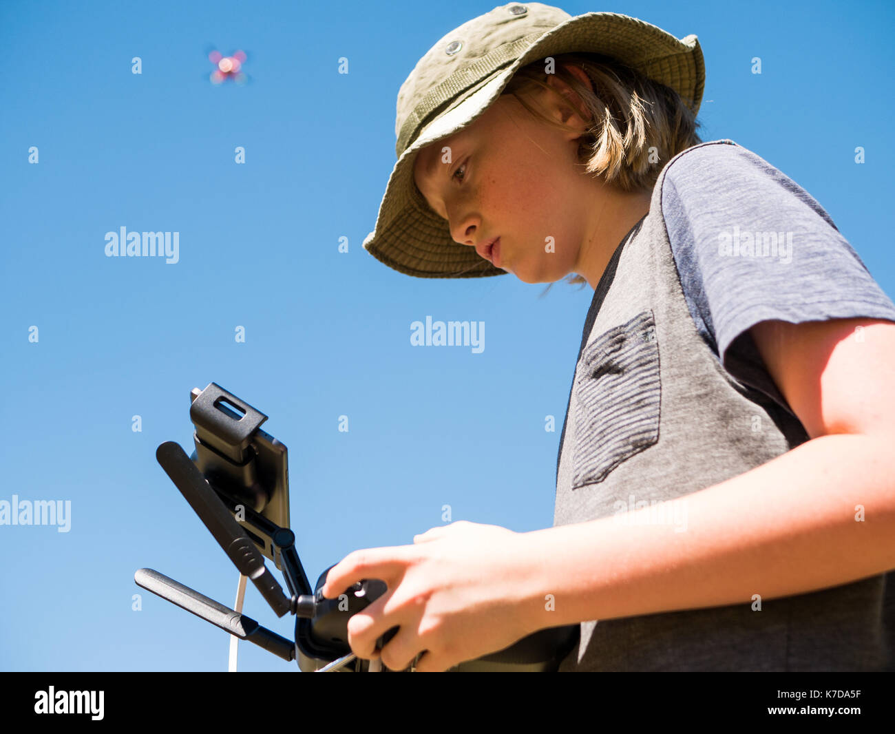 Low angle view of boy flying quadcopter using remote control against clear sky Stock Photo