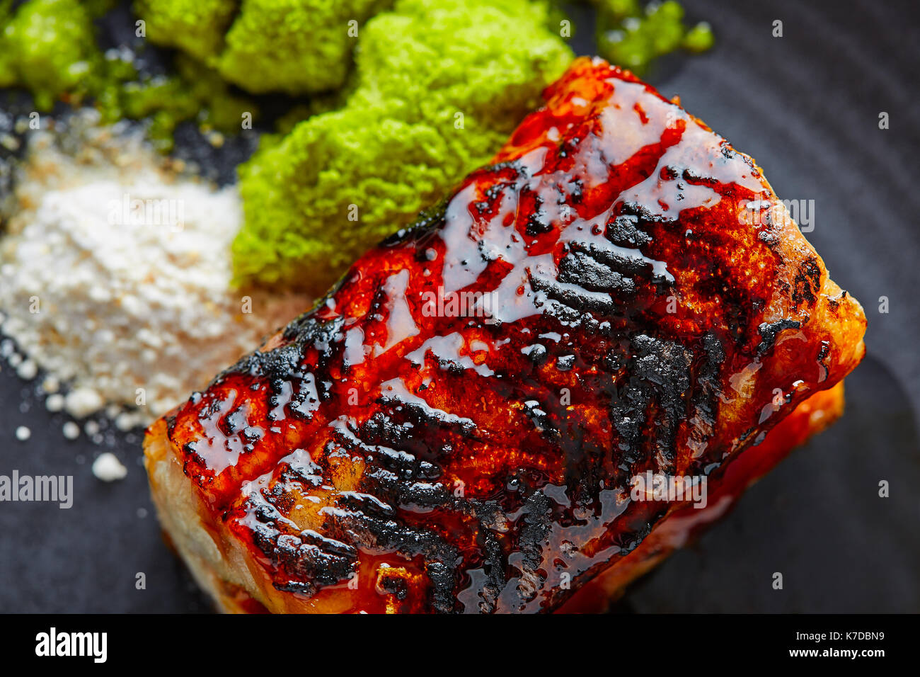 Grilled smoked eel with green apple and citrus on black plate Stock Photo