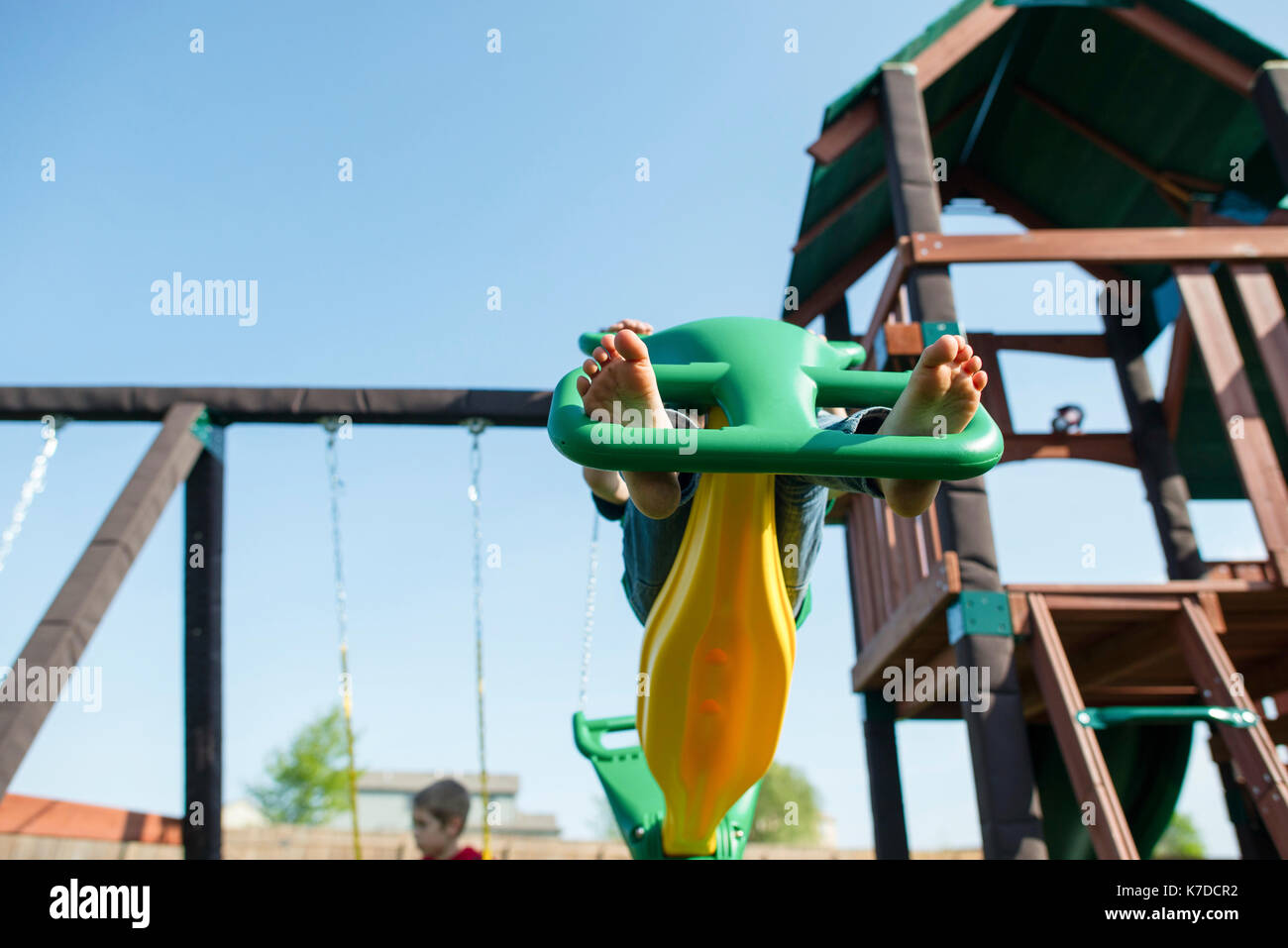 Low angle view of girl playing on outdoor play equipment against clear sky Stock Photo