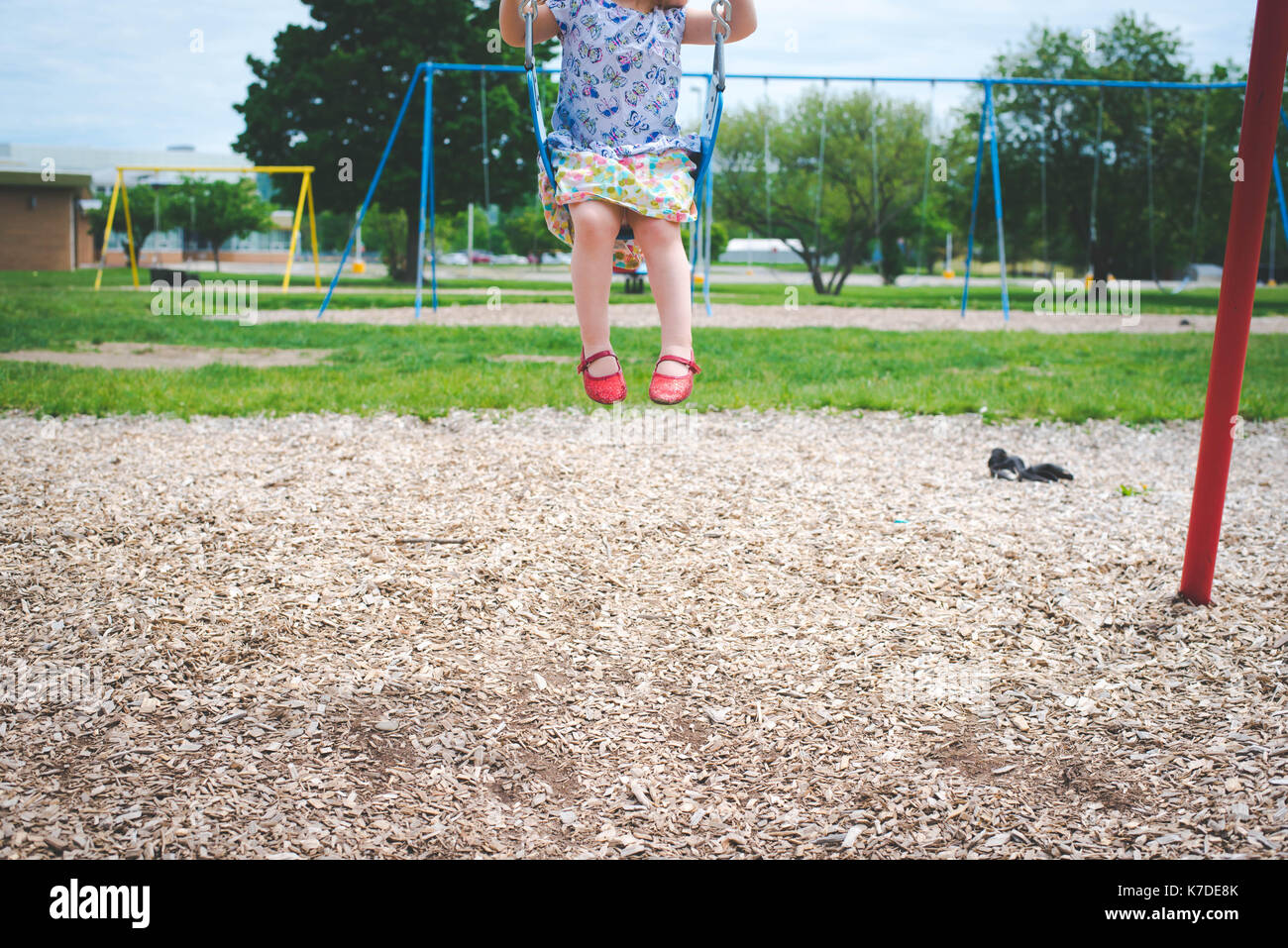 Low section of girl swinging at playground Stock Photo