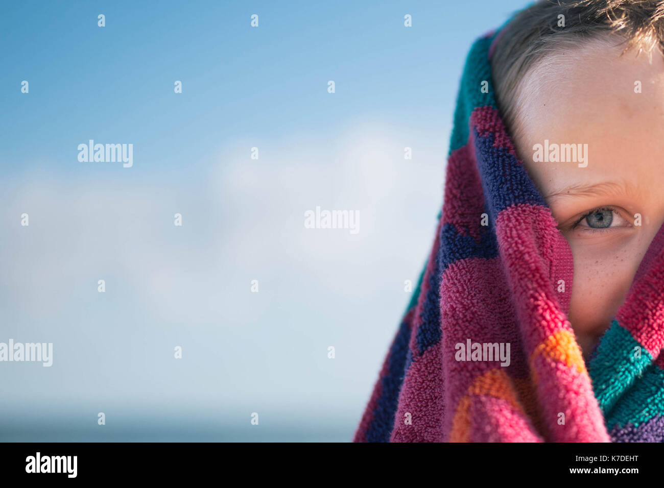 Cropped image of boy wrapped in towel against sky Stock Photo