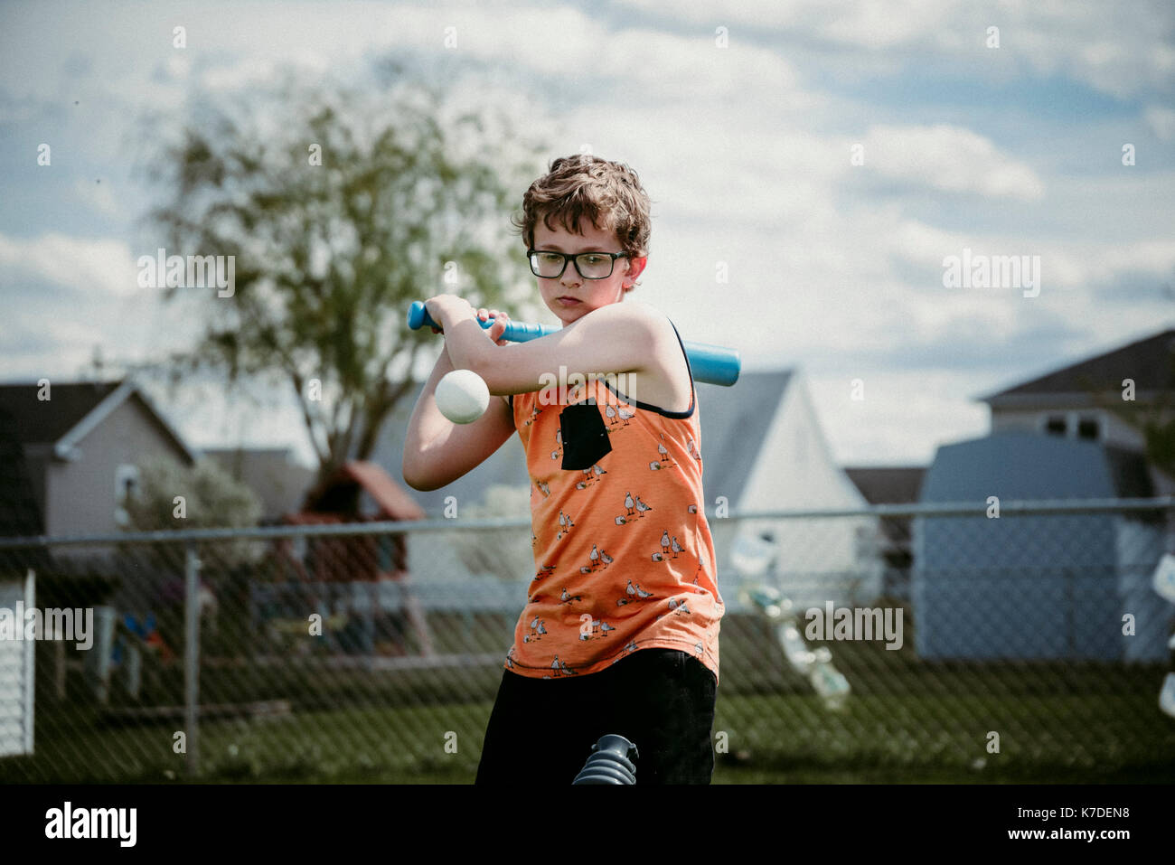 Teenage boy hitting ball while standing on playing field Stock Photo