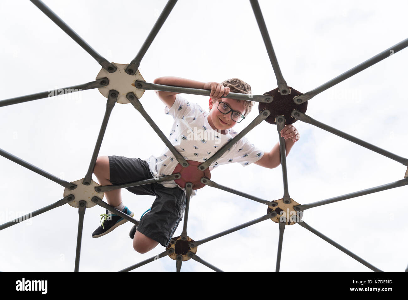 Portrait of boy on jungle gym at playground against clear sky Stock Photo