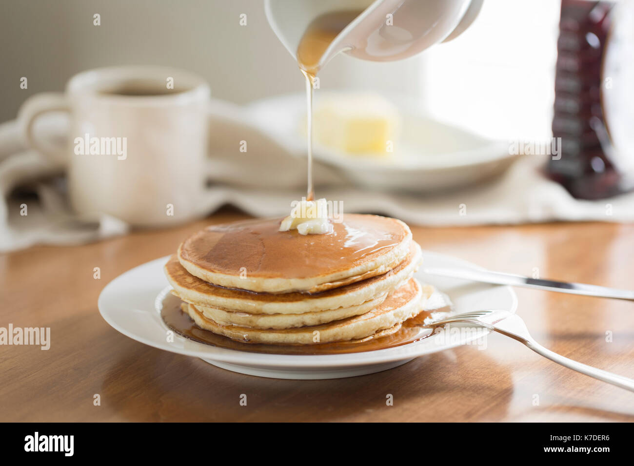 Cropped image of jug pouring honey on pancakes Stock Photo