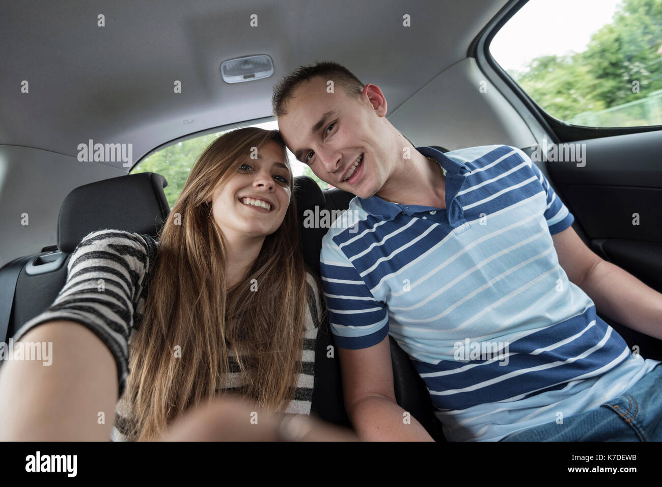 Portrait of happy couple sitting on car during vacation Stock Photo