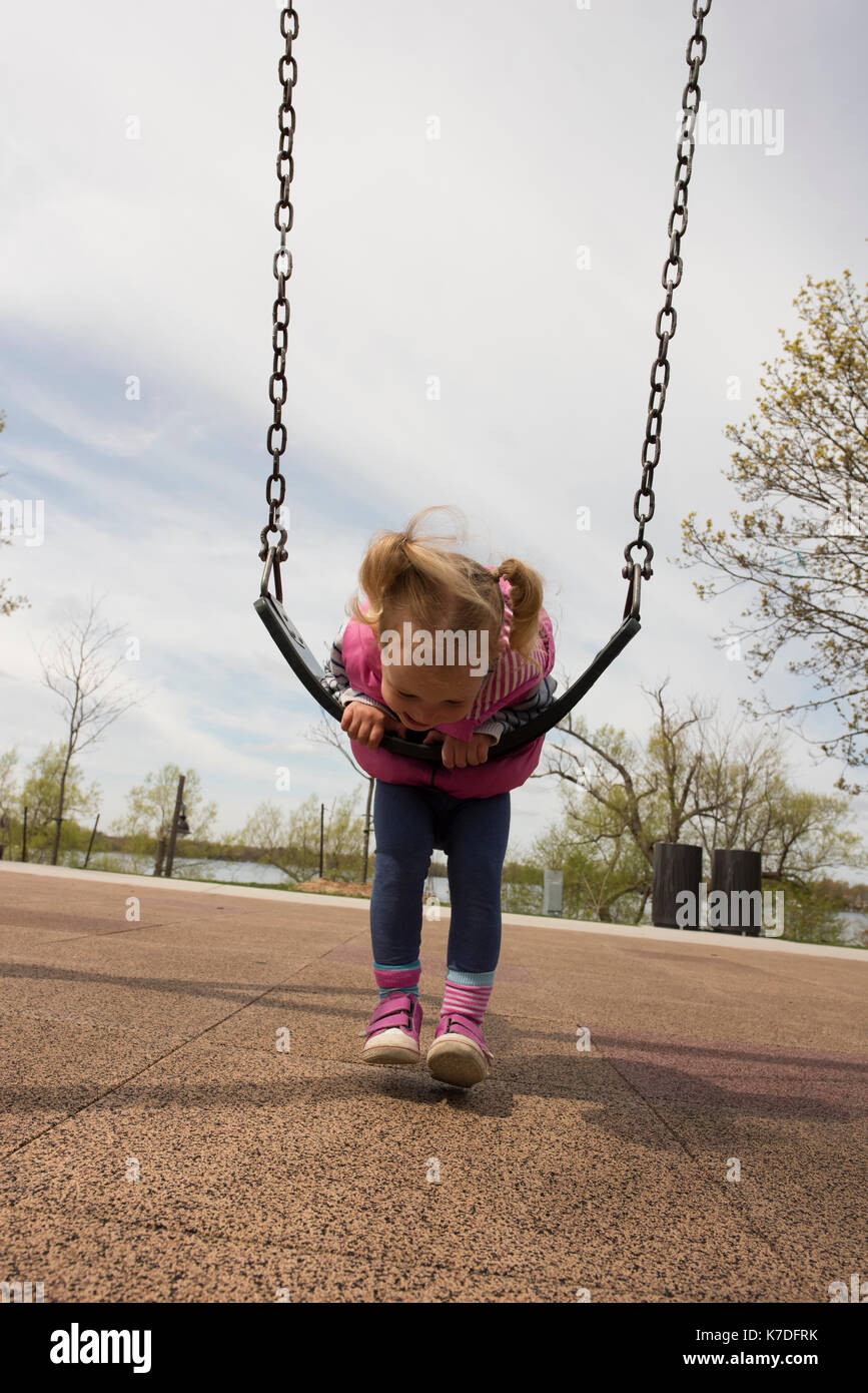 Full length of playful girl leaning on swing against cloudy sky Stock Photo