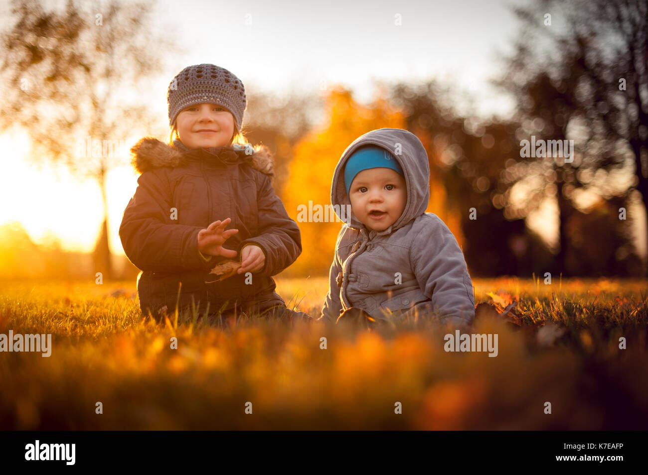 siblings sitting in the field in autumn Stock Photo