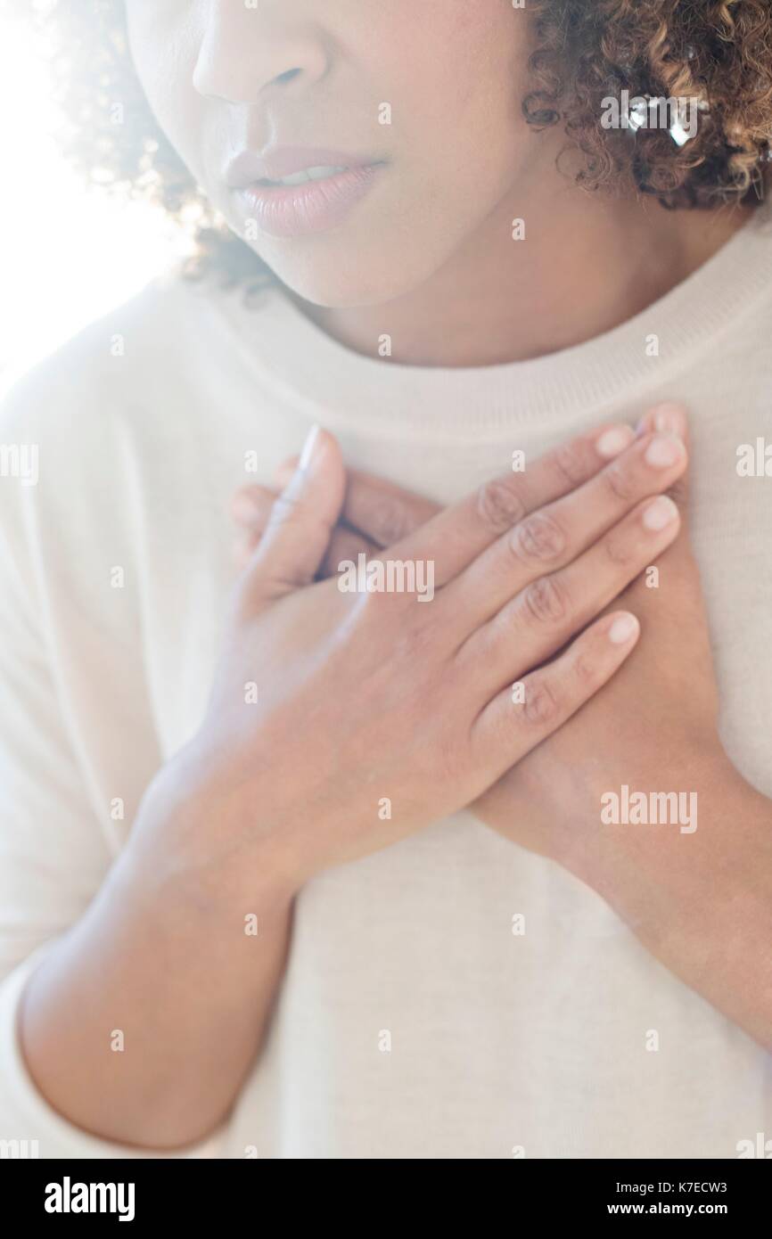 Mid adult woman touching her chest. Stock Photo