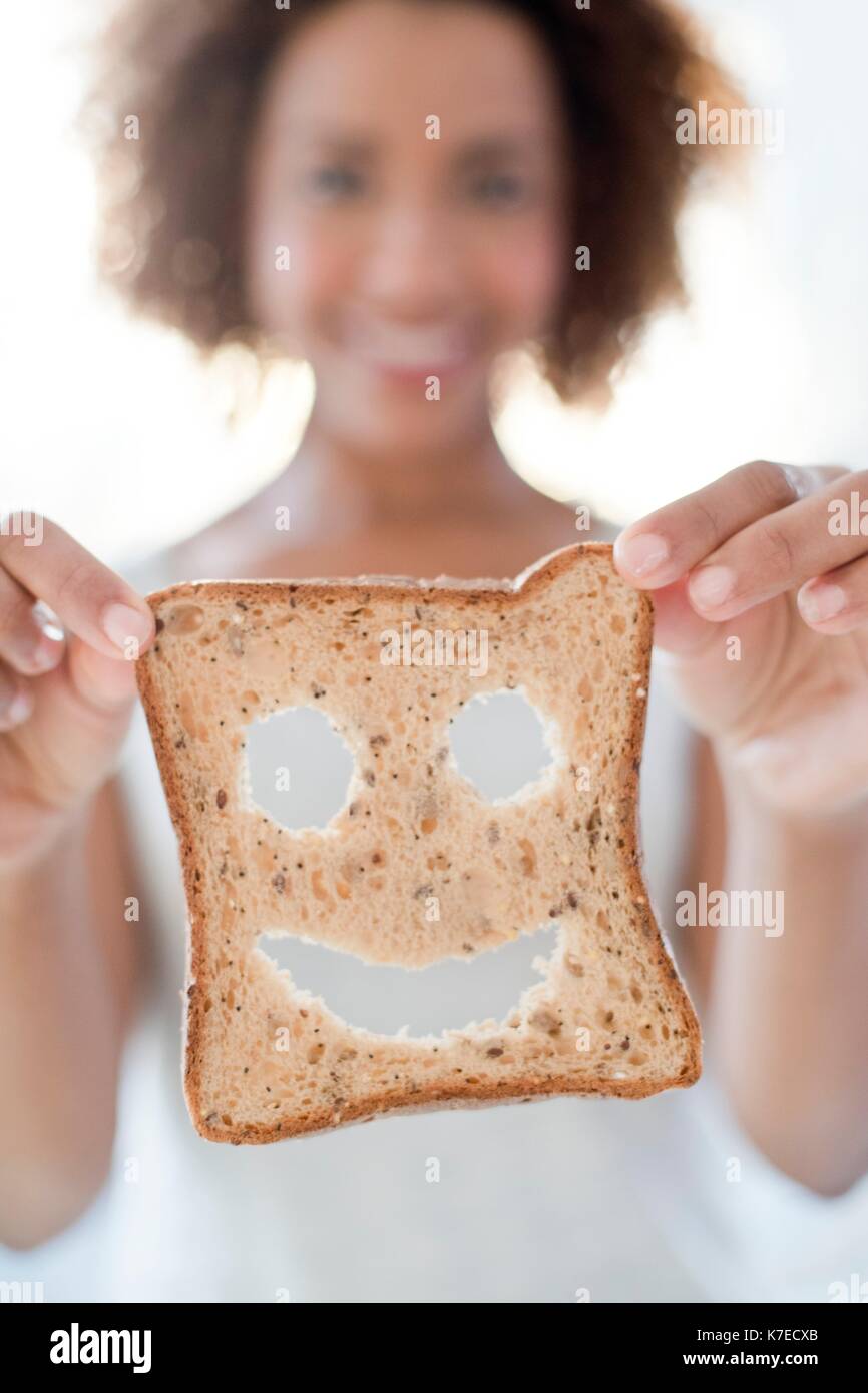 Mid adult woman holding bread with smiley face. Stock Photo