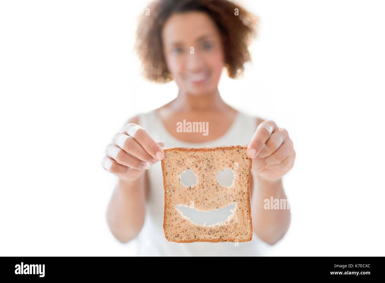 Mid adult woman holding bread with smiley face. Stock Photo