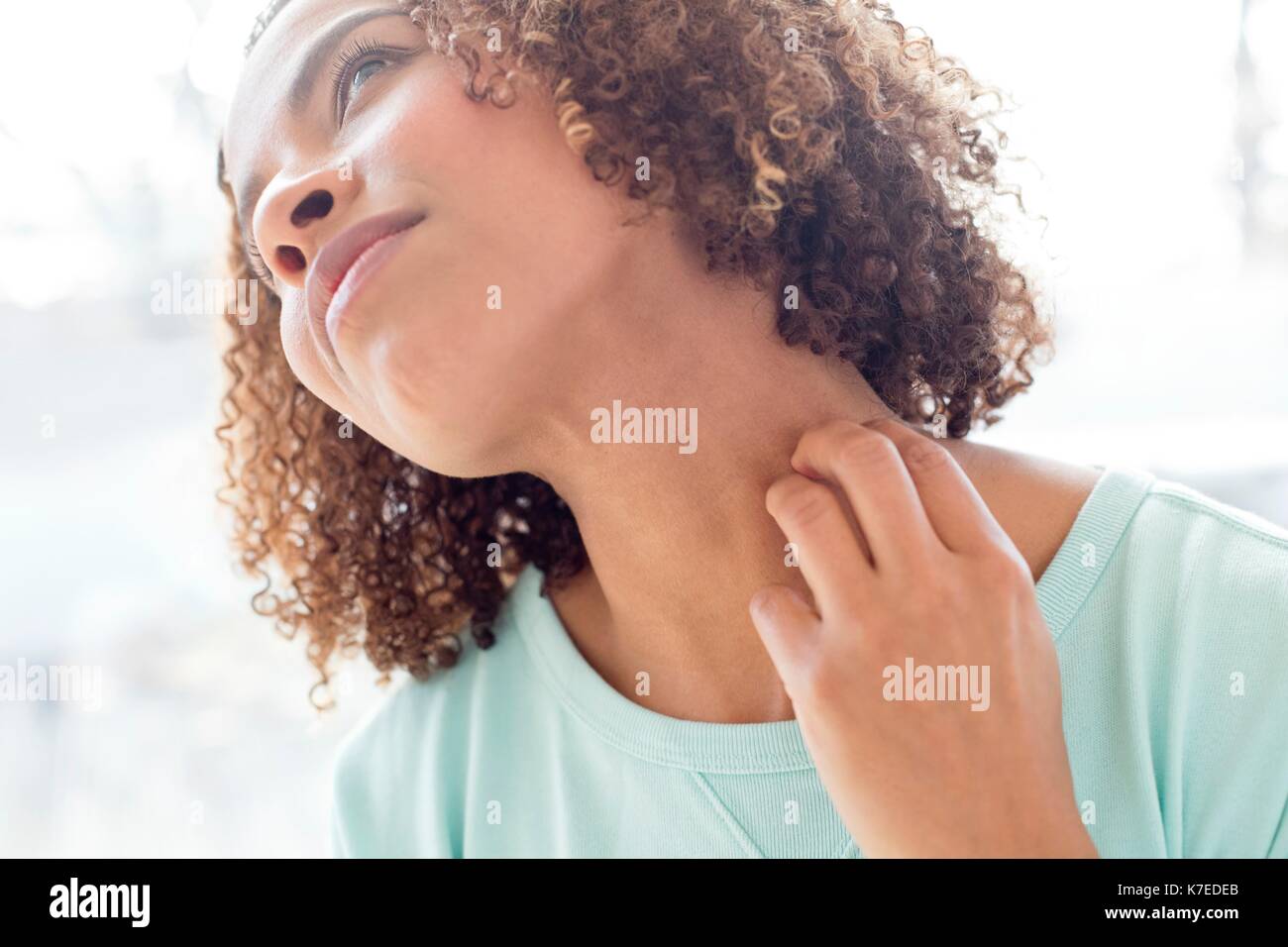 Mid adult woman scratching neck. Stock Photo