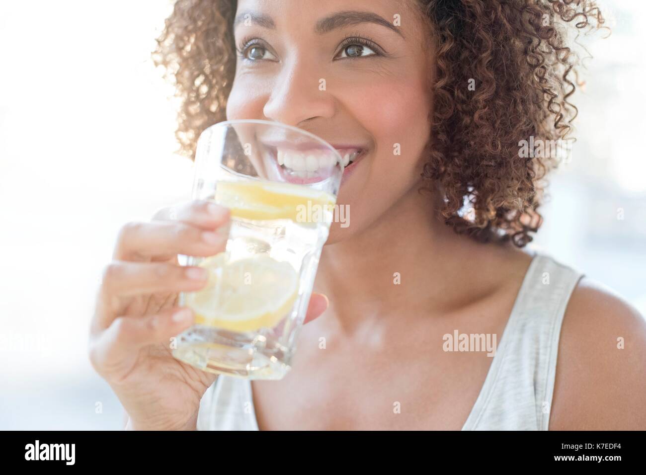 Mid adult woman drinking water with a slice of lemon. Stock Photo