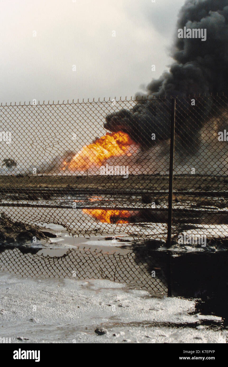 Burning oil well in field coated in spilled oil in aftermath of Operation Desert Storm, Persian Gulf War following the Iraq invasion of Kuwait. Stock Photo