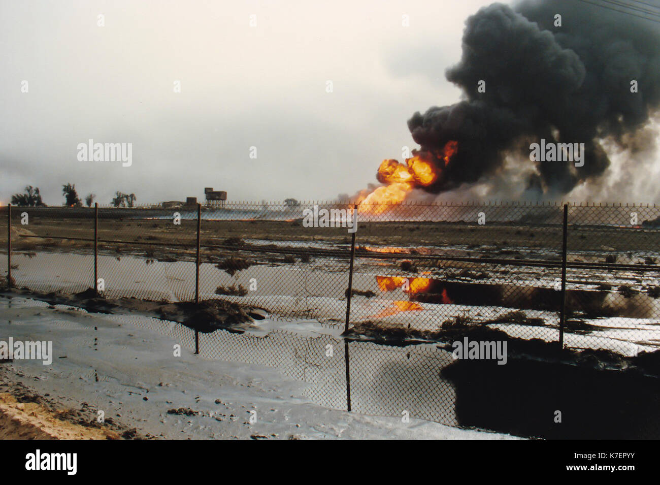 Burning oil well in field coated in spilled oil in aftermath of Operation Desert Storm, Persian Gulf War following the Iraq invasion of Kuwait. Stock Photo
