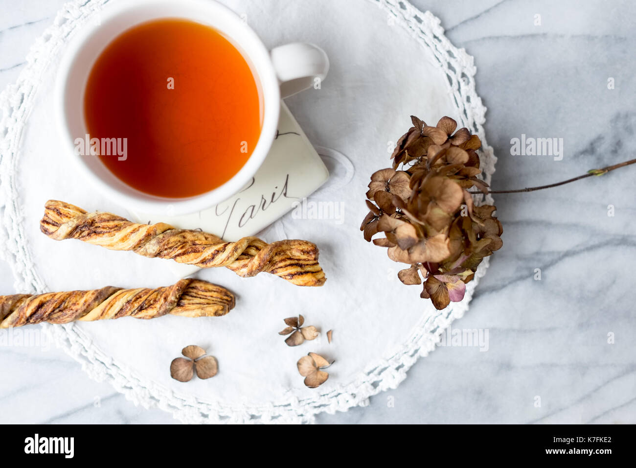 Cup of tea and cinnamon twist cookies on marble table. Paris coaster. Top view. Stock Photo
