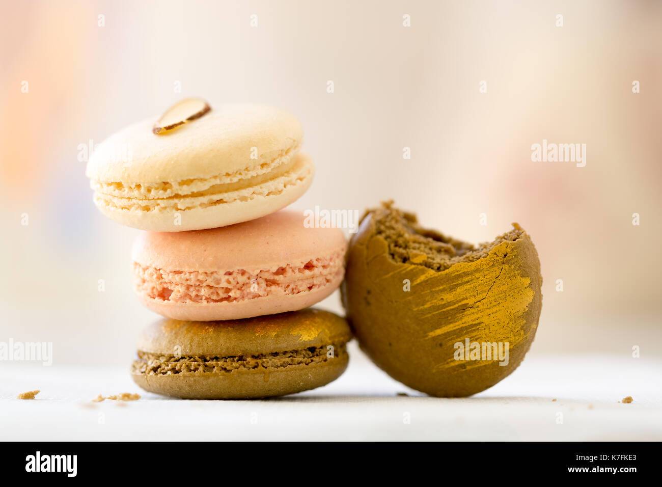Macaroon cookies stacked pastel colors selective focus. Edible gold painted decoration. Bite out of one cookie Stock Photo