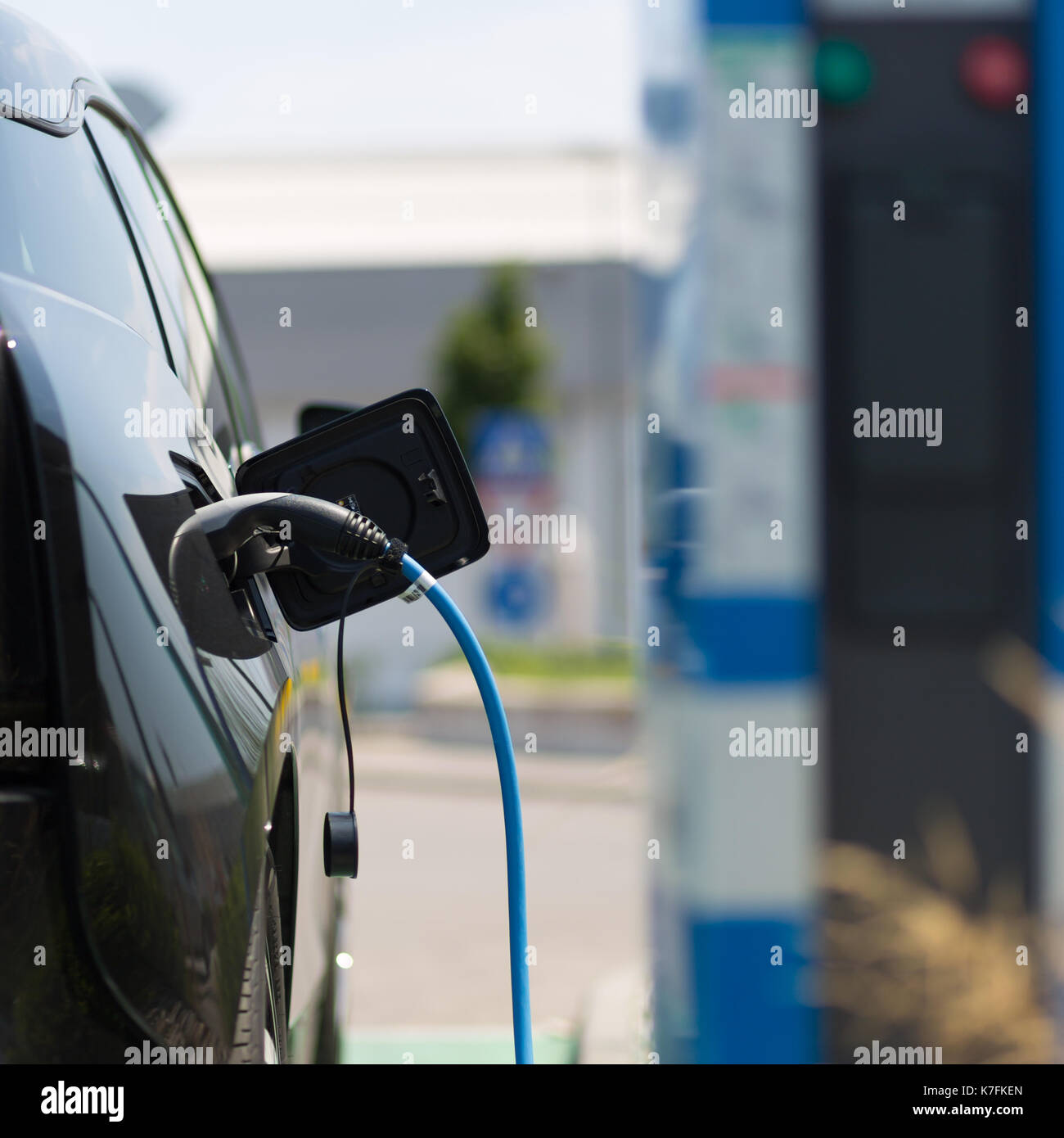 Power supply plugged into an electric car being charged. Stock Photo