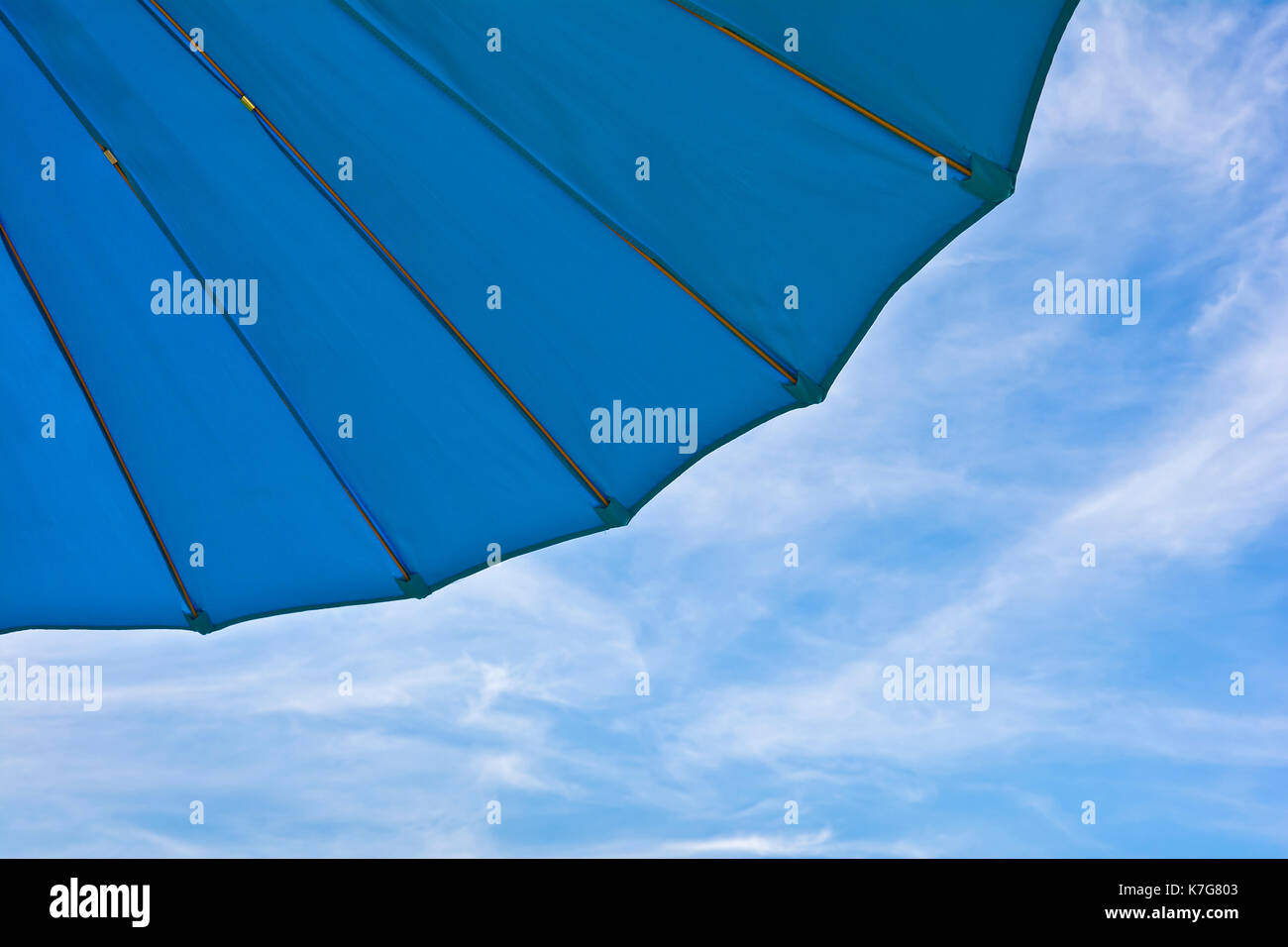 Fragment of a blue garden umbrella against the sky with clouds. Stock Photo