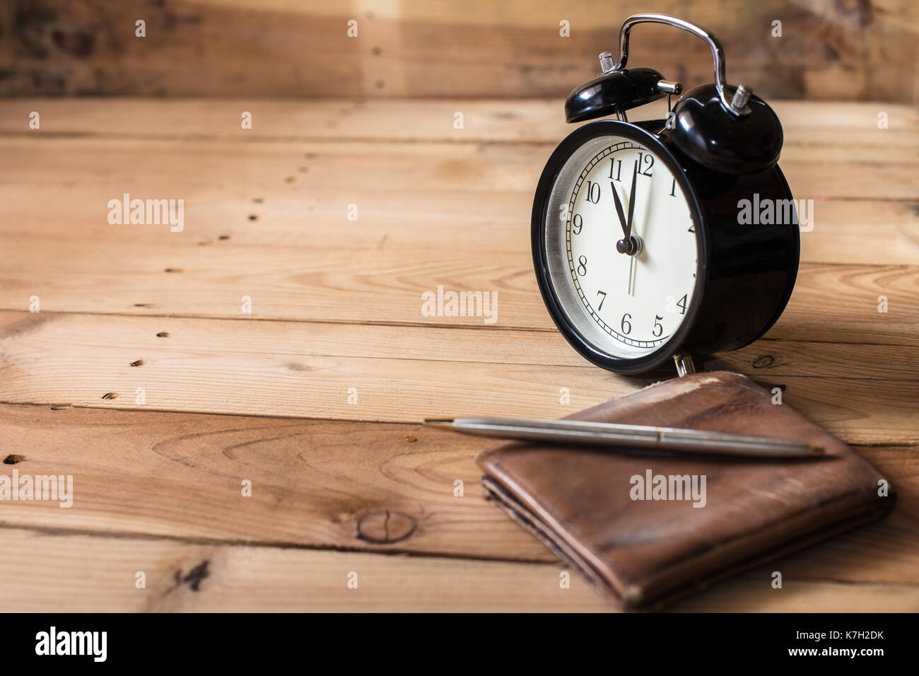 time to payment concept. retro bell clock timed at 11 o'clock on wood background with old leather wallet Stock Photo