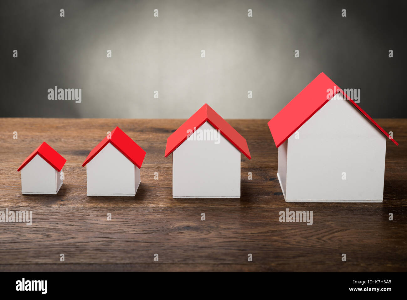 Different Size Houses In Row On Wooden Table Stock Photo