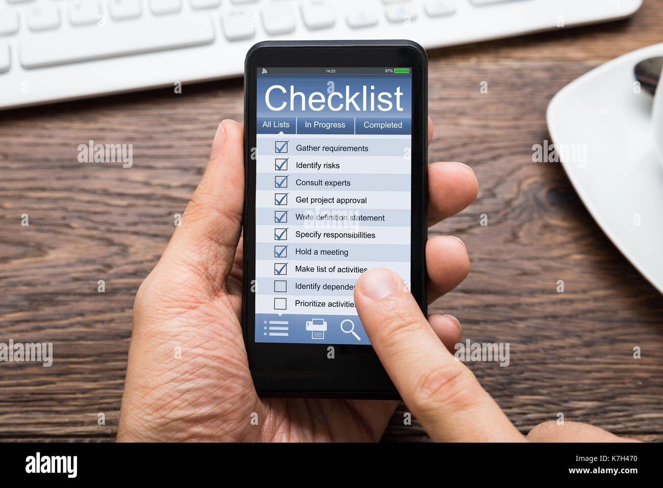 Close-up Of Person Hands Filling Checklist On Mobile Phone At Wooden Desk Stock Photo