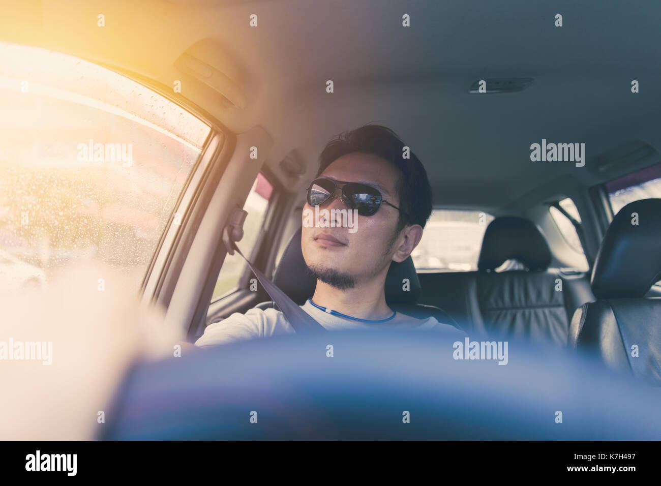 Asian Thai Chinese man male ware black sun glass drive a car in hot summer day travel. Stock Photo