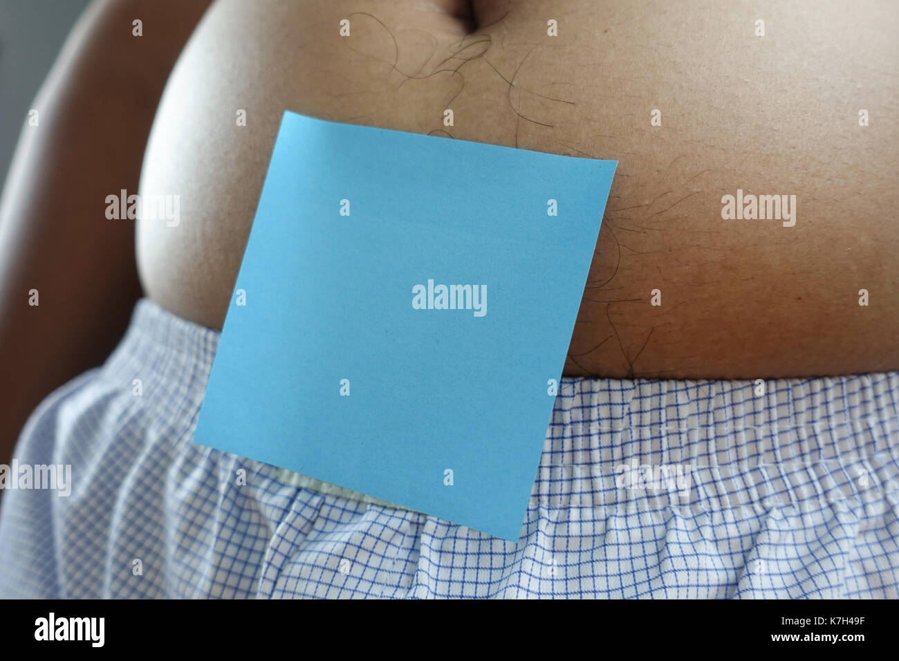 belly of a fat man with blue post note paper sticker - closeup Stock Photo