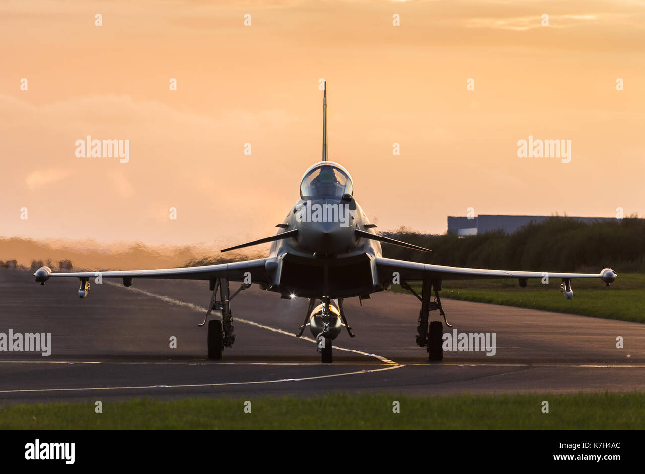 A Royal Air Force Typhoon jet taxis out towards the runway at Liverpool John Lennon airport at sunset ready for takeoff. Stock Photo
