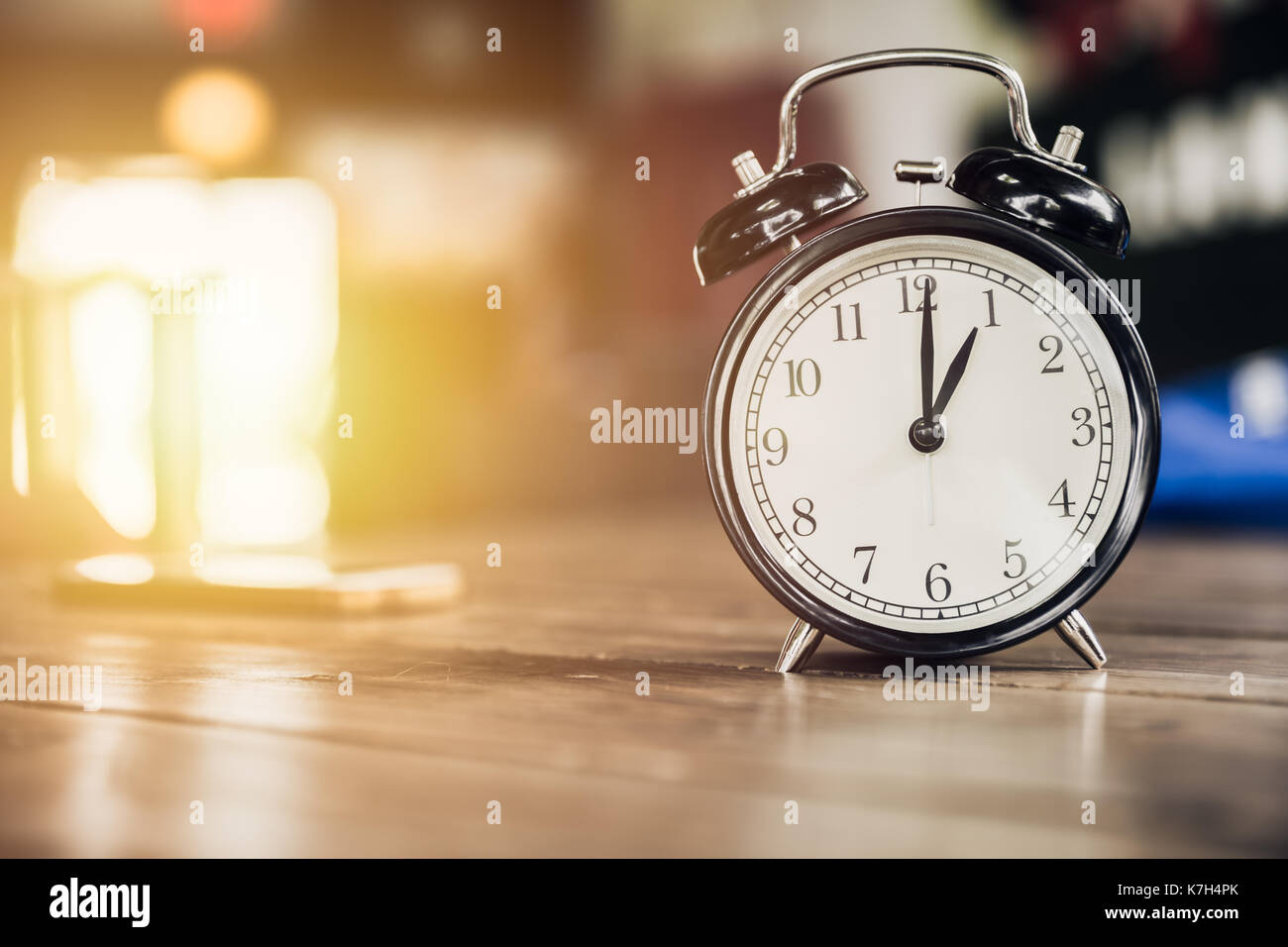 1 o'clock time retro clock on wood table with sun light background