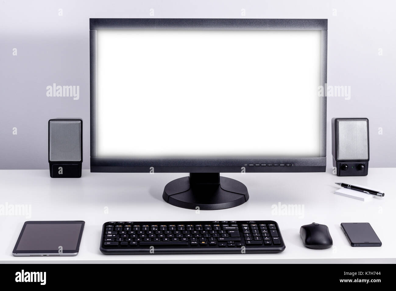 Blank white pc monitor on desktop in organized workplace. Stock Photo