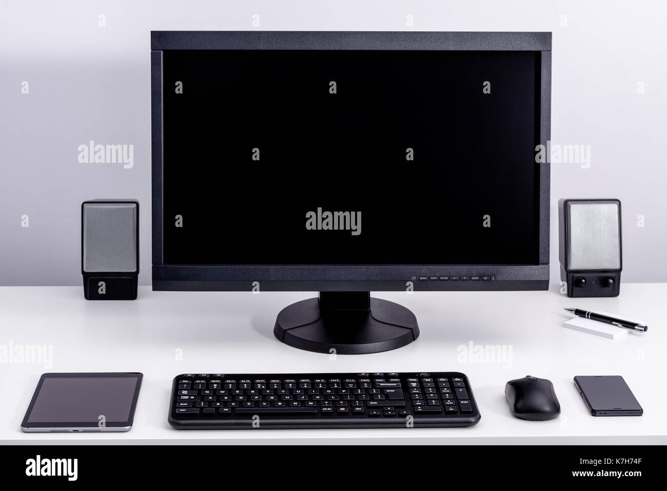 Blank black pc monitor on desktop in organized workplace. Stock Photo