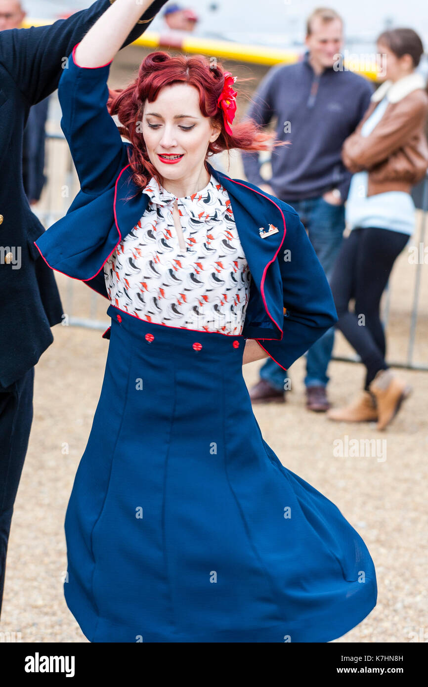 Young couple dancing in 1950s clothing. Woman in blue skirt and jacket, man in Royal Navy officer's uniform, during the Salute to the 40's popular weekend at Chatham Historic Dockyard. Stock Photo