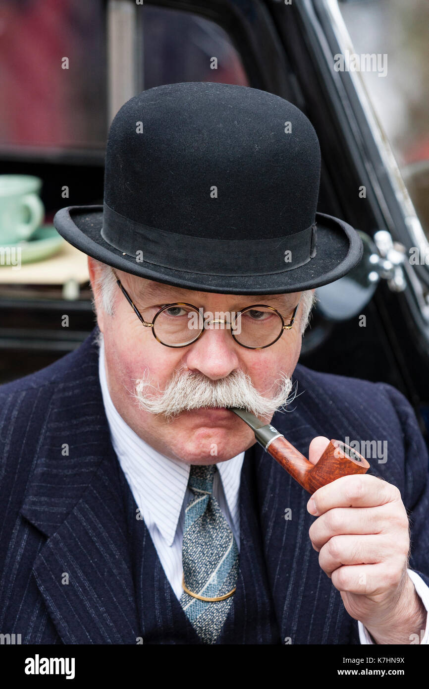 England, Chatham Dockyard. Event, Salute to the forties. Elderly man, in his 60s, with moustache, black suit and bowler hat. Smoking a pipe. Wearing 1940's period business suit. Stock Photo