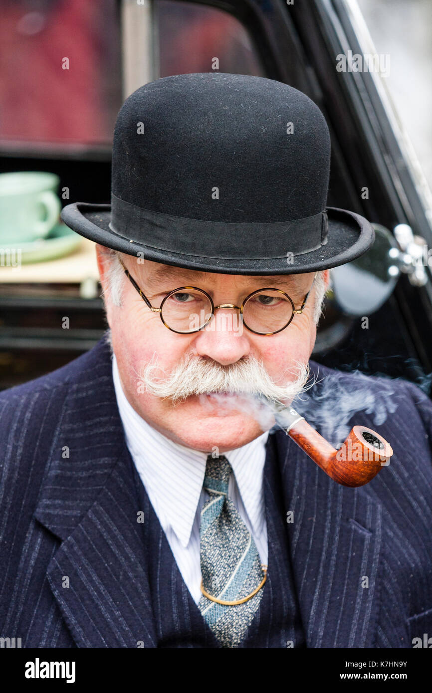 England, Chatham Dockyard. Event, Salute to the forties. Elderly man in his 60s, with moustache, black suit and bowler hat. Smoking a pipe. Stock Photo