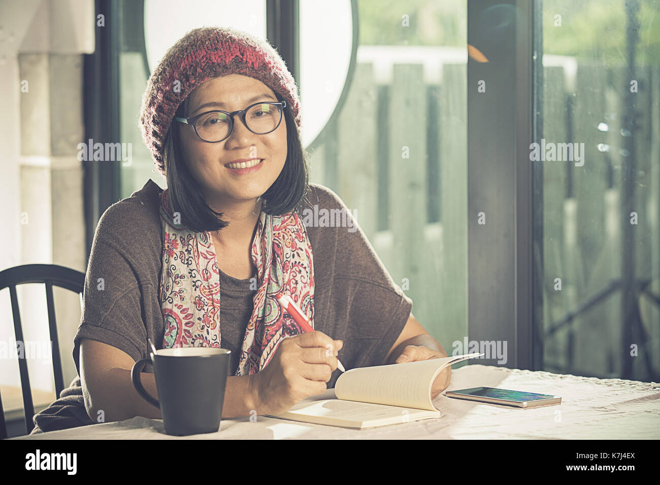 toothy smiling face of asian woman reading pocket book in coffee shop Stock Photo