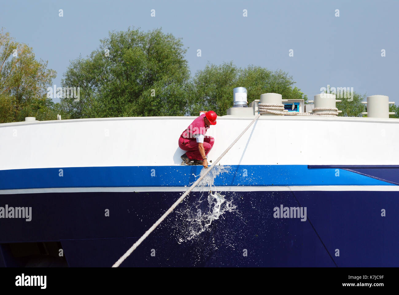 worker smashing a bottle of champagne on the new ship Stock Photo