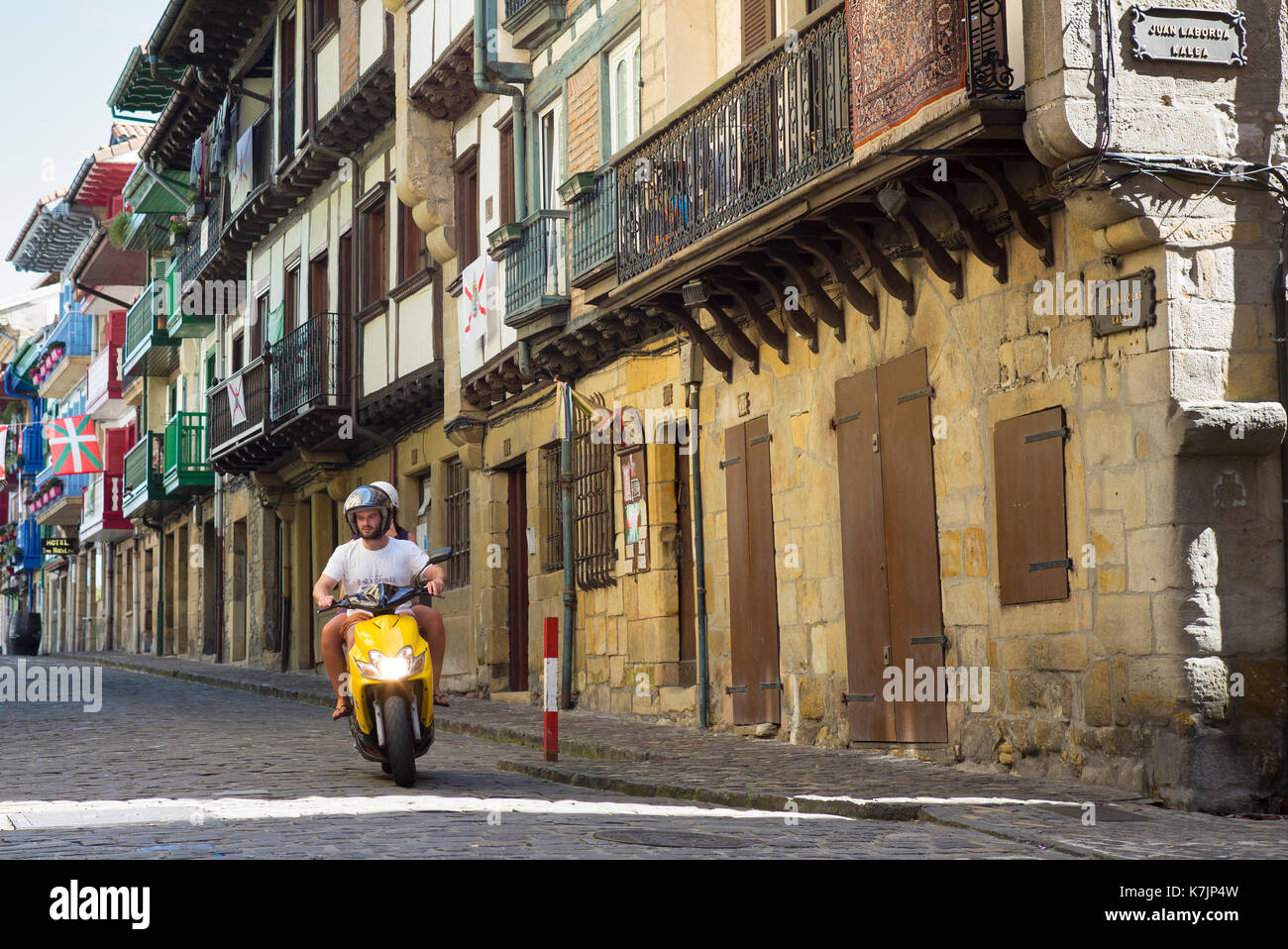 Motorcyclist on cobbled street passing medieval half-timbered architecture in Hondarribia, in Basque Country, Spain Stock Photo