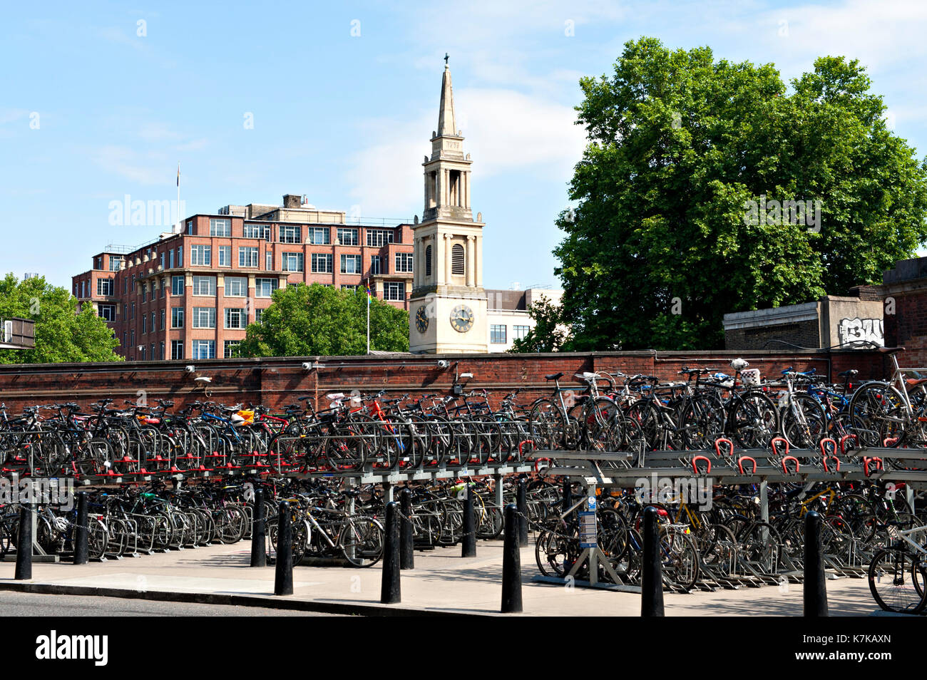 Bicycles stored in two tier racks outside London Waterloo Railway Station with St John's Church in the background Stock Photo